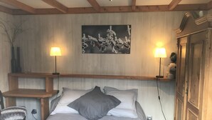 Une chambre à coucher comprenant un lit, deux lampes de chevet, un bureau, une chaise, une armoire et un tableau accroché au mur.