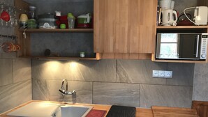 Une cuisine équipée d’un évier, d’un plan de travail et de meubles de rangement en bois.