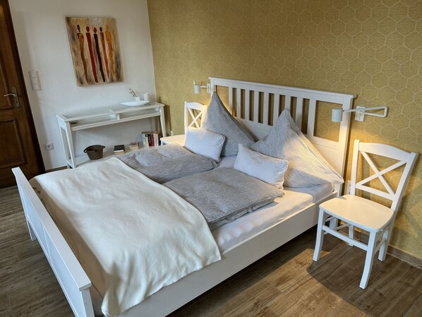 Un lit bien fait, avec une tête de lit blanche, une table de chevet avec une lampe et une chaise.