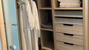 Een inloopkast met meerdere planken, lades en ruimte om kleding op te hangen.