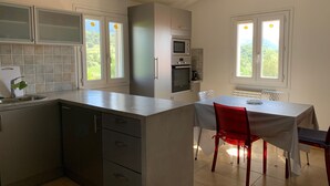 Een moderne keuken met een eetgedeelte, met een inbouwoven, magnetron en uitzicht op het landschap door de ramen.