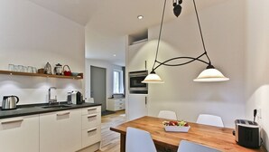 Una cocina moderna con armarios blancos, una mesa de comedor de madera y una lámpara colgante.