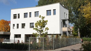 Un edificio moderno de dos plantas con fachada blanca y numerosas ventanas.