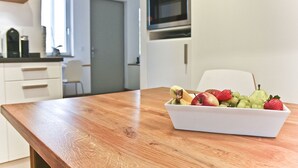 Una cocina con una mesa de madera, un microondas y un frutero sobre la mesa.