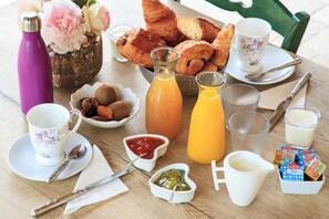 A breakfast table with croissants, pastries, a thermos, a pitcher of orange juice, a cup of coffee, a bowl of fruit, condiments, and a box of cereal. - ✨ A romantic bed-and-breakfast with a 150-square-meter private spa just for you! (Noyant-Et-Aconin)