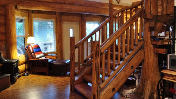 A wooden staircase with a rustic interior, a leather chair, a lamp, and a television. - The Heron House (Olympia)