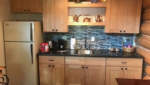 A kitchen with wooden cabinets, a stainless steel sink, and a refrigerator. - The Heron House (Olympia)