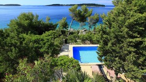 Una piscina envoltada d'arbres amb vista al mar i illes a la distància.