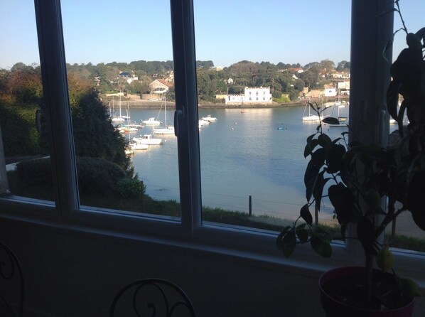 A view of a harbor with boats, a white building, and a hill with trees.