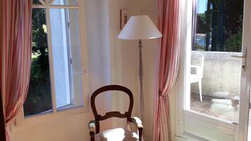 A room with a wooden chair, a lamp, and a window with curtains.