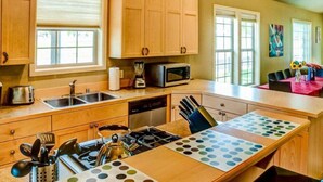 Une cuisine avec des meubles en bois, un four à micro-ondes, une cuisinière et un coin repas comprenant une table et des chaises.