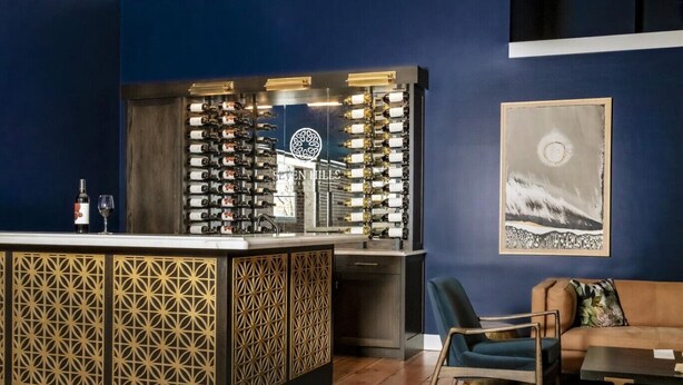 Un coin bar avec un présentoir à bouteilles de vin, un canapé et un tableau accroché au mur.