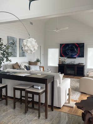 Una sala de estar moderna con comedor, chimenea y televisor grande.