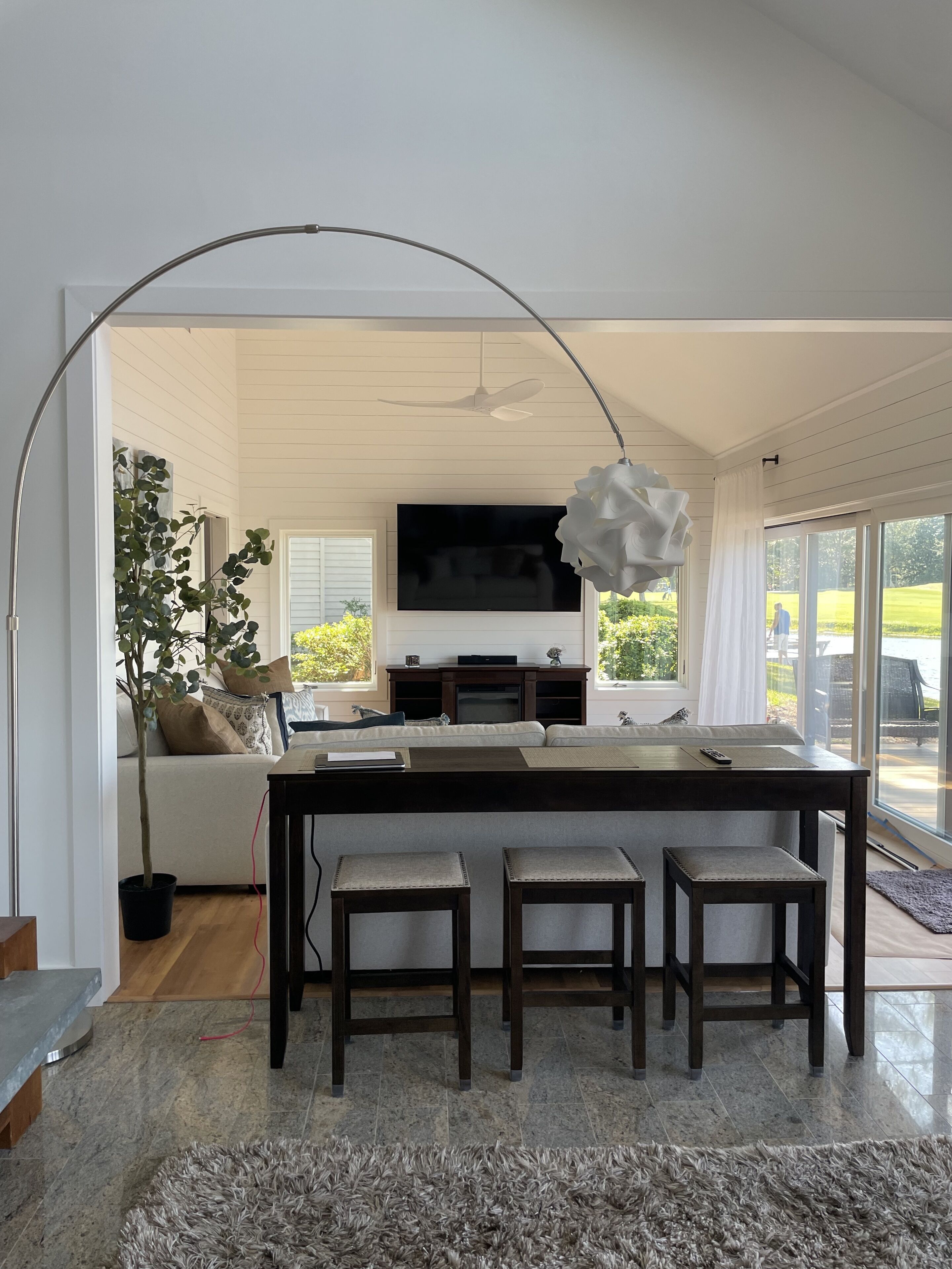 A modern living room with a central island, a large flat-screen TV, and a dining area with a table and chairs.