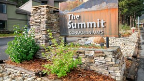 Une enseigne indiquant « The Summit Condominiums », avec un mur en pierre et de la verdure autour.