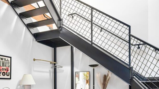 Un interior moderno con una escalera, un sofá de cuero y una pequeña mesa.