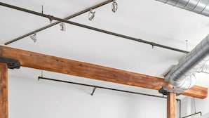 Una cocina moderna con gabinetes negros, electrodomésticos de acero inoxidable y vigas de madera a la vista.