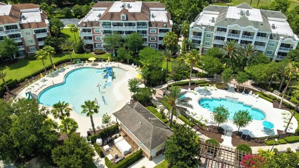 Ein Hotel mit großem zentralen Pool, mehreren Balkonen und üppiger Bepflanzung.