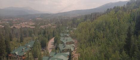 Un resort con varias edificaciones, cada una con techos verdes, rodeado de un bosque denso y montañas al fondo.