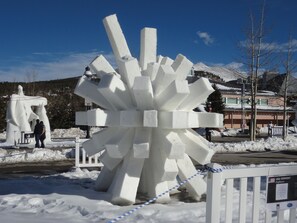 A large white ice sculpture in a snowy outdoor area with a mountain in the background.