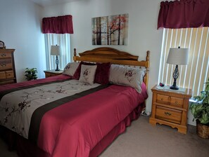 A neatly made bed with a floral bedspread, a wooden headboard, and two bedside tables with lamps.