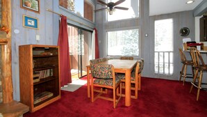 Ein Essbereich mit Holztisch und Stühlen, einem Deckenventilator und einem Bücherregal.