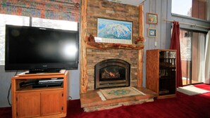 Ein Wohnzimmer mit Kamin, Fernseher und Bücherregal.