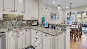 A kitchen with white cabinets, granite countertops, and pendant lighting. - Award-Winning Resort Amenities | Racquet Club Villa 6 (Isle of Palms)