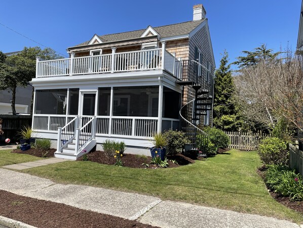 Une maison à deux étages avec un balcon, une véranda et un petit jardin.