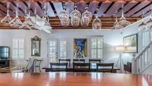 A spacious dining area with a wooden table and chairs, a chandelier, and artwork on the walls. - Beach Block Living in Charming South Rehoboth. (Rehoboth Beach)