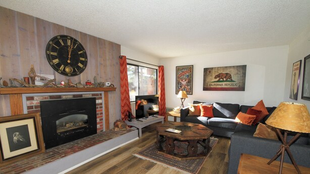 A living room with a fireplace, a sofa, a coffee table, and a clock on the wall. - Mammoth Ski & Racquet Club #114 -Pet Friendly (Mammoth Lakes)