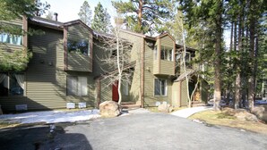 A two-story wooden building with a garage, surrounded by trees and a snow-covered ground. - Forest Creek #3, Pet accepted (Mammoth Lakes)