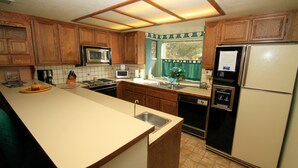 A kitchen with wooden cabinets, a microwave, a toaster, a sink, and a refrigerator. - Forest Creek #3, Pet accepted (Mammoth Lakes)