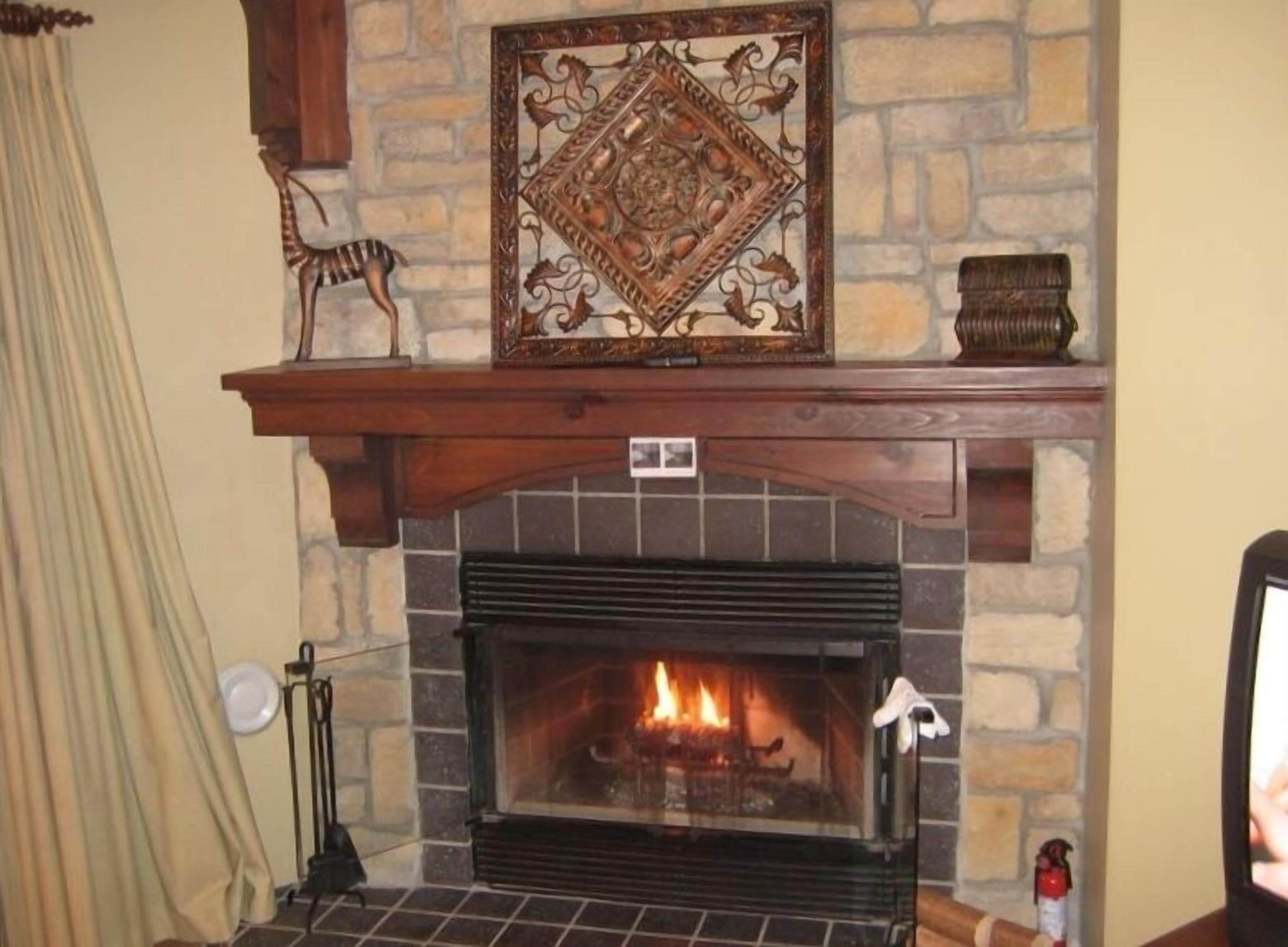 A fireplace with a stone mantle, a decorative plate, and a small figurine.
