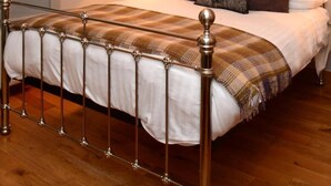 A bedroom with a bed, a chandelier, a bedside table with a lamp, and framed pictures on the wall. - Rothay Villa (Ambleside)