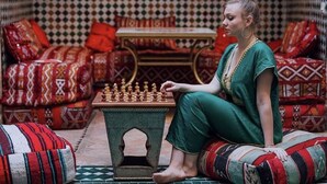 A person sitting on a patterned sofa with a chessboard in front of them. - Riad Ali Baba (Marrakech)