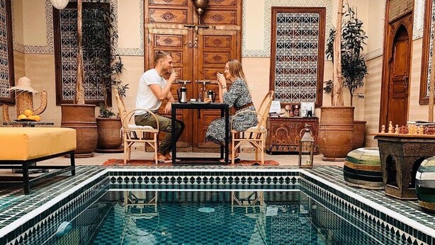 A courtyard with a pool, wooden doors, and a table with chairs. - Riad Ali Baba (Marrakech)