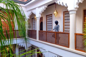 A traditional Moroccan courtyard with ornate wooden doors, lattice windows, and hanging lanterns. - Riad Ali Baba (Marrakech)