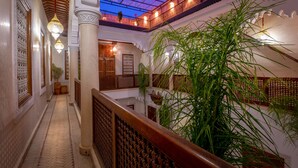 A corridor with a wooden railing, hanging lanterns, and a large plant. - Riad Ali Baba (Marrakech)