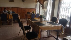 Un comedor con mesas y sillas, una planta en maceta y vistas por una ventana.