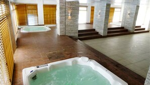 A spa area with two hot tubs and a stone wall. - Rio de Janeiro Season. Bora Bora Barra - Complete Leisure Resort - Barra da Tijuca - RJ (Rio de Janeiro)