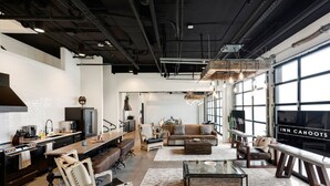 A modern hotel interior with a kitchen, dining area, and living room. - Inn Cahoots on 6th: 10BR/26Bed - Pool,Roofdeck, Garden Bars, Walk To Everything! (Austin)