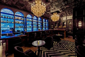 A bar area with shelves of bottles, chandeliers, and seating. - Inn Cahoots on 6th: 10BR/26Bed - Pool,Roofdeck, Garden Bars, Walk To Everything! (Austin)