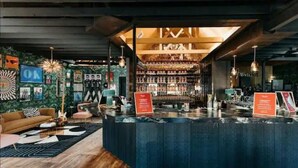 A bar area with a counter, shelves of bottles, and a sign. - Inn Cahoots on 6th: 10BR/26Bed - Pool,Roofdeck, Garden Bars, Walk To Everything! (Austin)