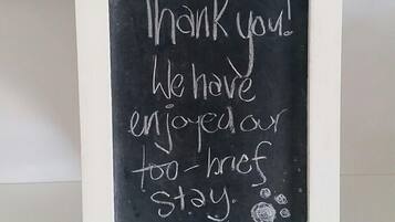 A chalkboard sign with a message, set against a painting of a sailboat on water.