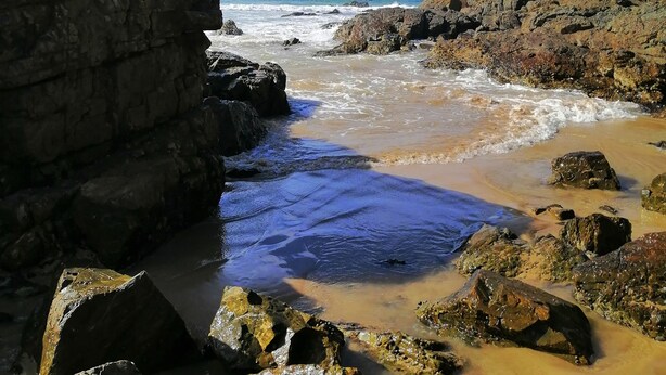 A rocky beach with waves gently crashing onto the shore.