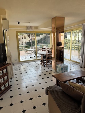 Ein Wohnzimmer mit einer Couch, einem Tisch und einem Balkon mit Sitzgelegenheiten.