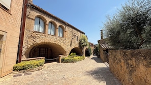 A stone building with arched doorways and a narrow cobblestone path. - Beautiful apartment with large terrace and spectacular views of Sant Pol bay (S'Agaró)