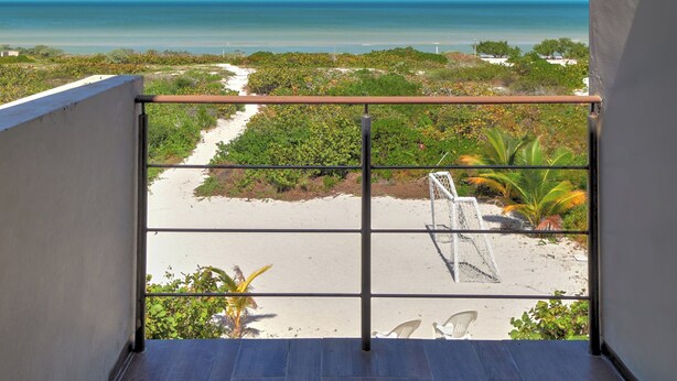 A balcony with a view of the beach and ocean.