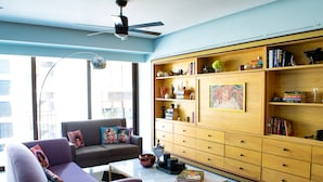 Un salon moderne avec un canapé, une table basse et une bibliothèque en bois remplie de livres et d’objets décoratifs.